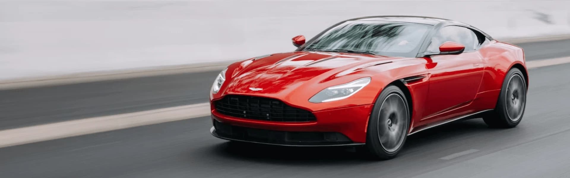 Um carro desportivo vermelho circula numa estrada suave, com um fundo desfocado que indica movimento.